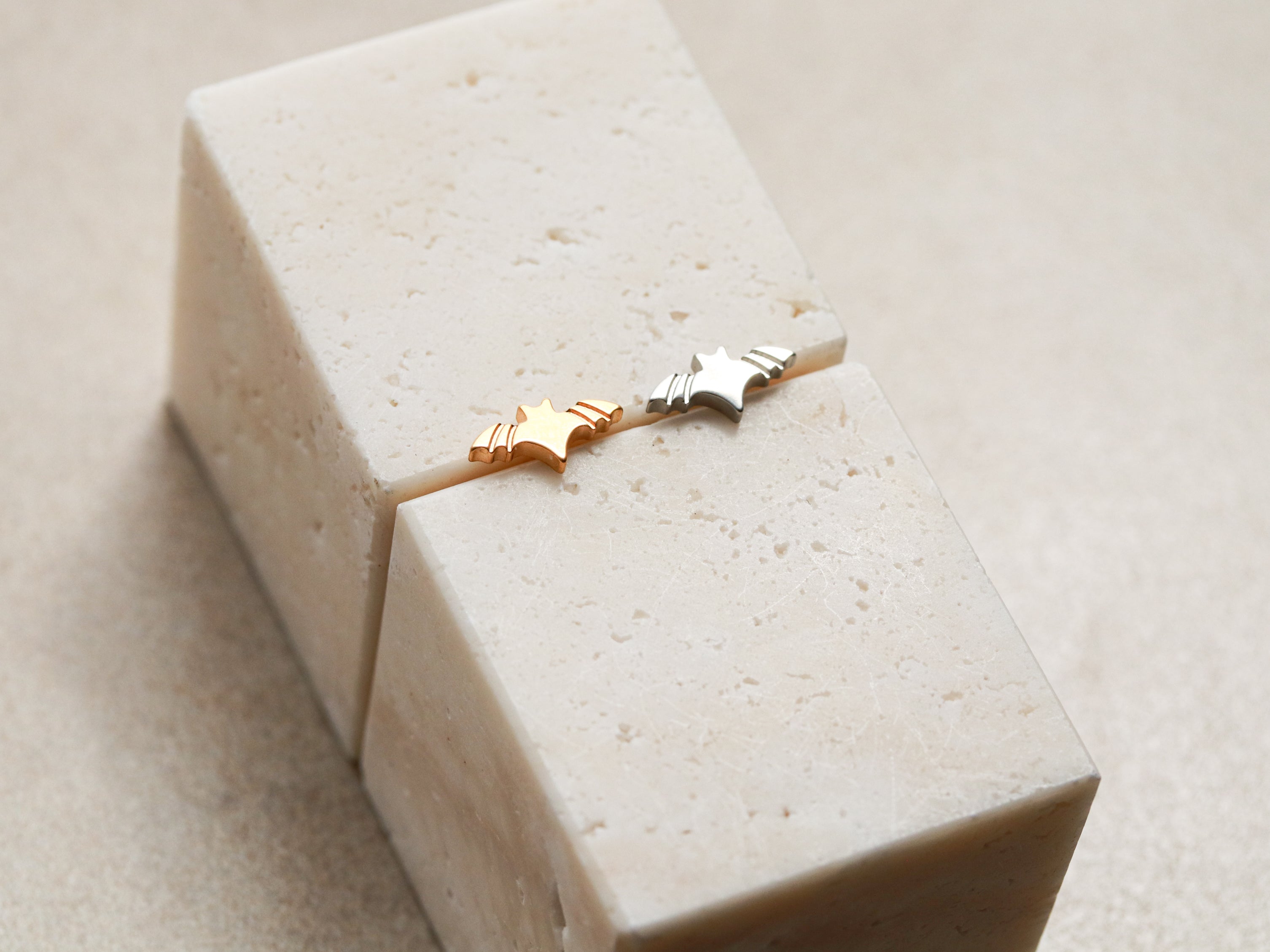 Two small star-shaped earrings are placed on a white rectangular block.