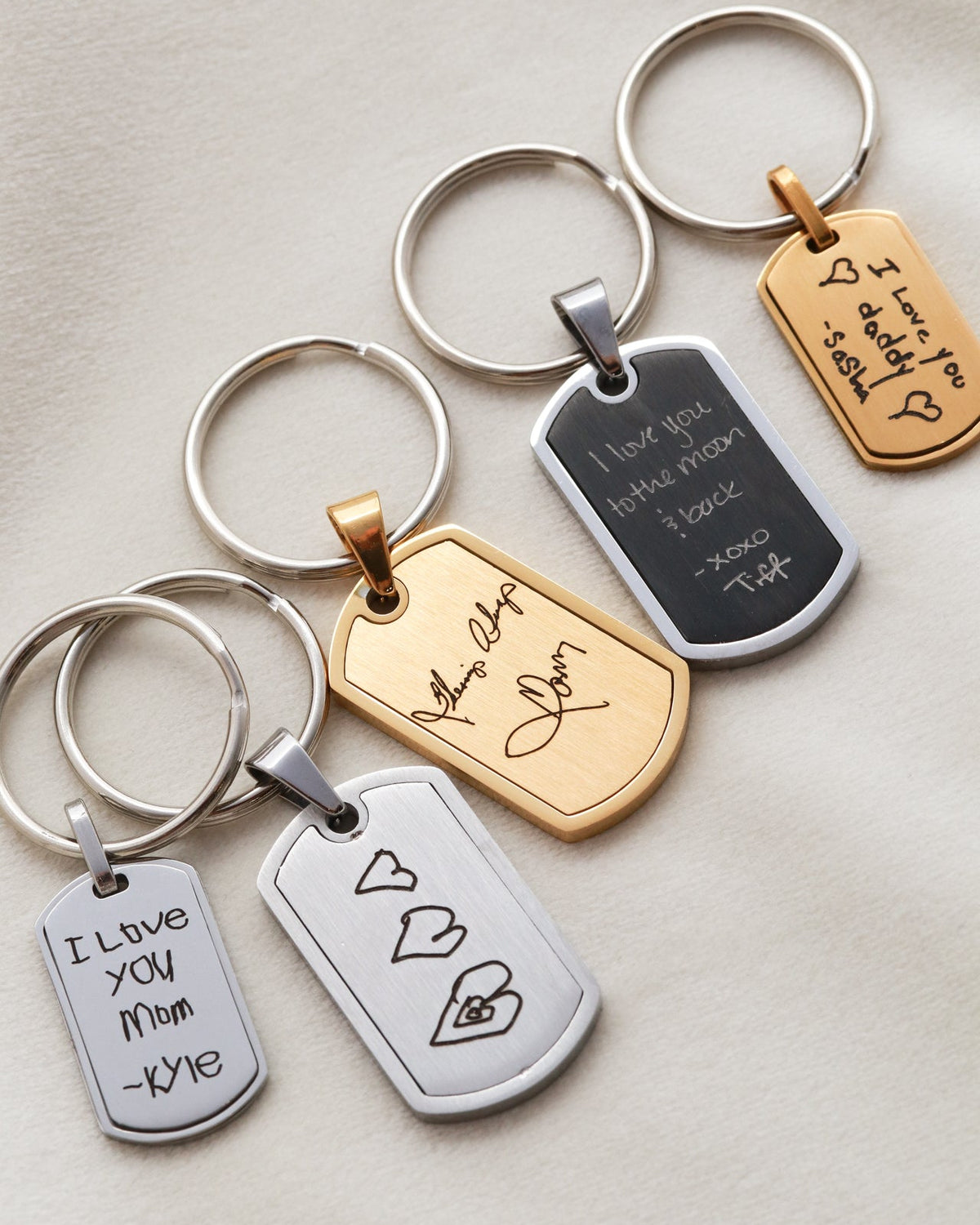 Collection of keychains with engraved text and designs on a neutral background
