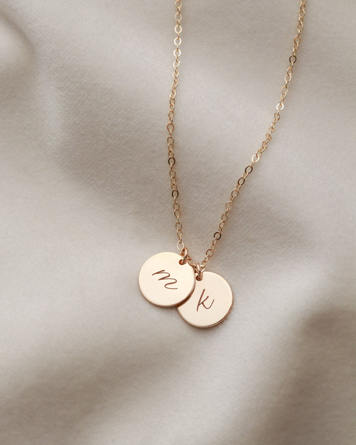 Rose gold necklace with two round pendants on a soft beige background