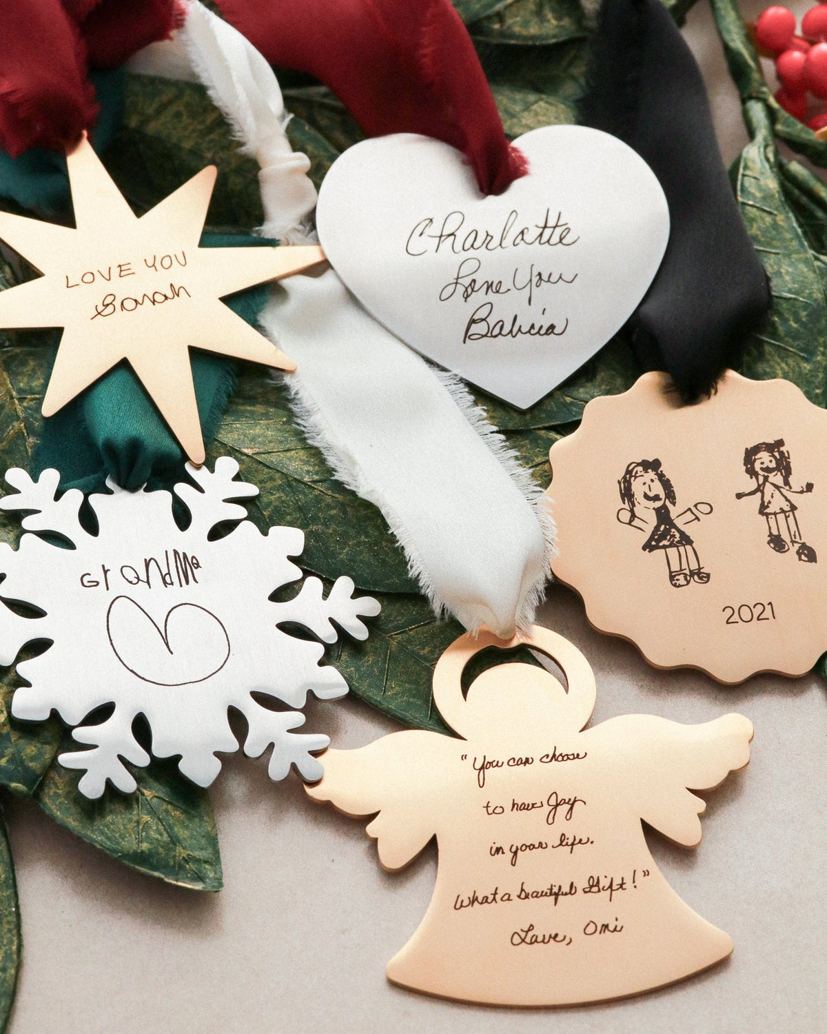 Decorative Christmas ornaments with engraved messages on a green leaf background