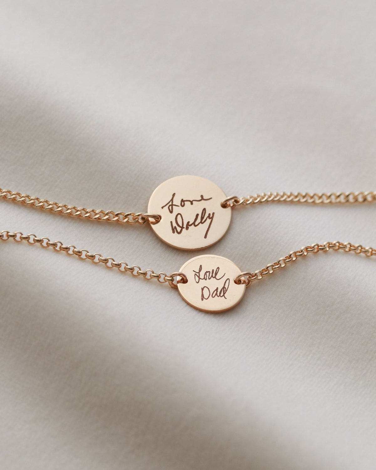 Two rose gold necklaces with engraved text on a light background