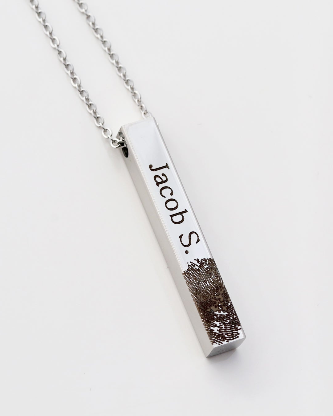 A stainless steel bar necklace with an engraved fingerprint on it, displayed on a white background.