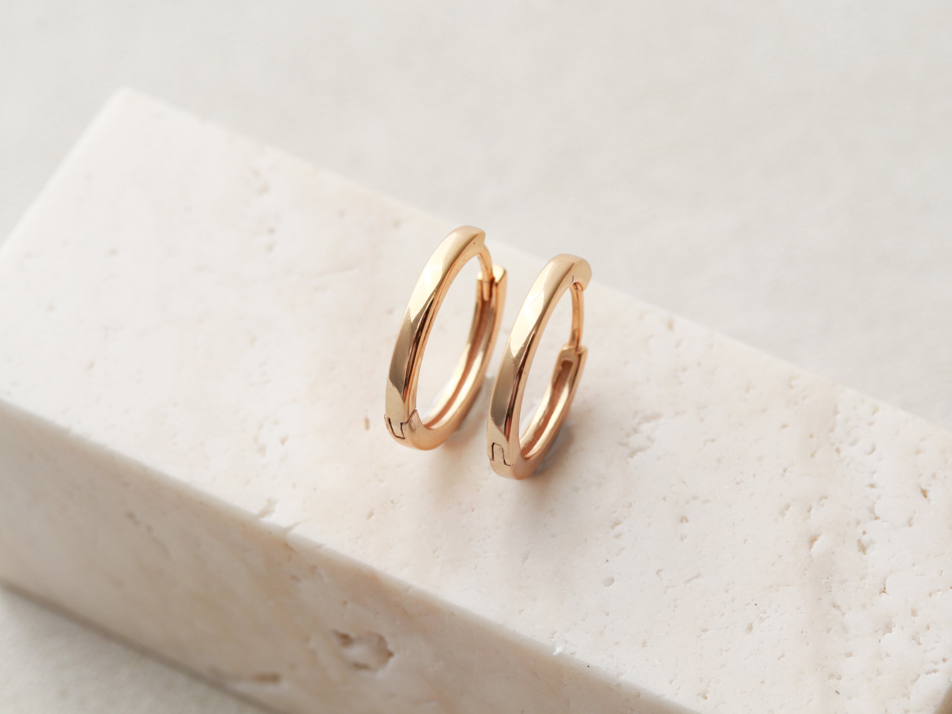 Pair of gold hoop earrings on a light stone surface