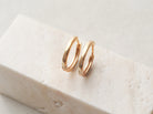 Pair of gold hoop earrings on a light stone surface