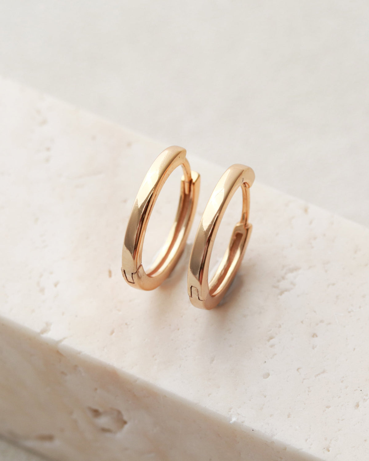 Pair of gold hoop earrings on a light stone surface