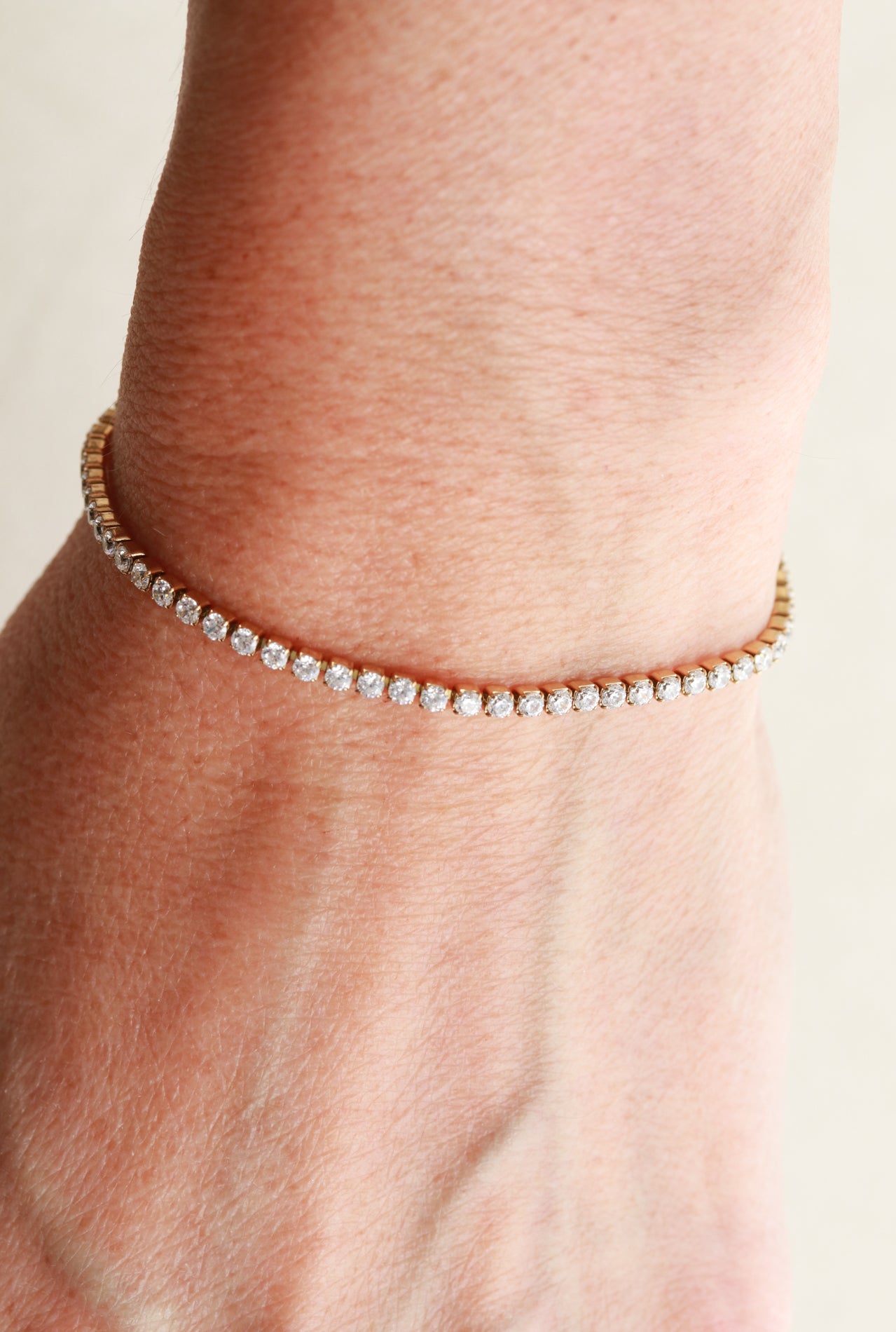 A gold bracelet with small diamonds on a person's wrist.
