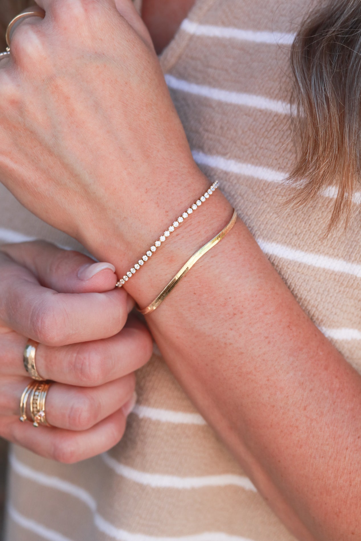A close-up view of a person's hand wearing a bracelet and a ring on their fingers.